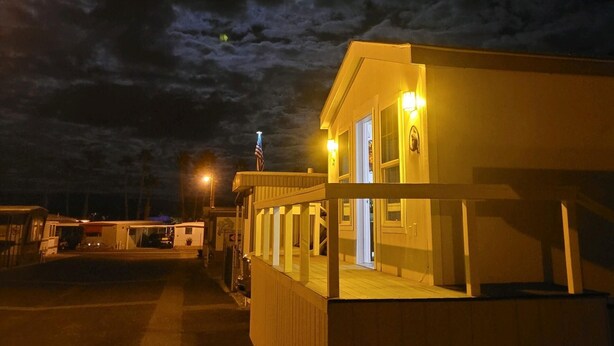 Een gebouw met een veranda en een vlaggenmast, onder een bewolkte lucht.