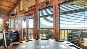 Un interno in legno con un tavolo rotondo, sedie e vista attraverso ampie finestre.