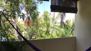 Ein Balkon mit Blick auf tropische Pflanzen und einer violetten Hängematte.