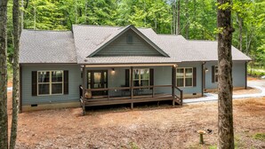 A two-story cabin with a porch, surrounded by trees.