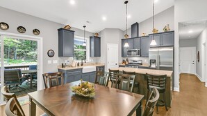A modern kitchen with dark cabinets, a central island, and pendant lighting.