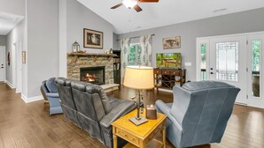 A living room with a fireplace, leather chairs, a wooden coffee table, and a ceiling fan.