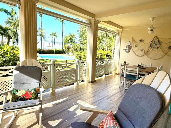 A sunlit room with a pool view, wooden flooring, and a table with chairs.