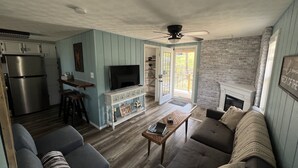 A modern kitchen with a built-in refrigerator and a dining area with a wooden table and bar stools. - Creek View, Covered Decks & Private Hot Tub, Woods, Peaceful, Wildlife! (Chillicothe)