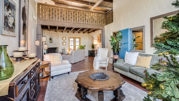 A spacious living room with a high ceiling, a fireplace, and a balcony. - Midtown home with Pool Spa, fire pit, close to U of A, Restaurants, & Shopping (Tucson)