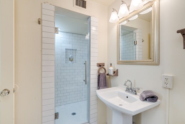 A bathroom with a glass shower enclosure, a sink, and a mirror. - Midtown home with Pool Spa, fire pit, close to U of A, Restaurants, & Shopping (Tucson)