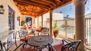 An outdoor patio with a wooden ceiling, a round table, and chairs. - Midtown home with Pool Spa, fire pit, close to U of A, Restaurants, & Shopping (Tucson)