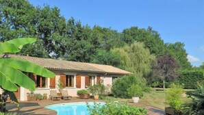 Una casa con piscina, rodeada de exuberante vegetación y árboles.