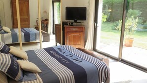 Un dormitorio con cama, televisión, puerta corrediza de vidrio a un jardín y un armario de madera.