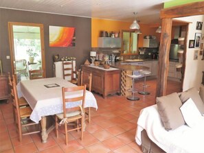 A dining area with a table and chairs, a kitchen with a stove and cabinets, and a living area with a sofa.