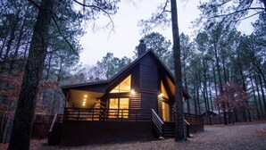 A cabin with a front porch, wooden exterior, and a chimney.