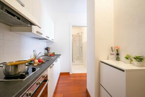 A narrow kitchen with a stove, sink, and cabinets.