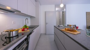 A modern kitchen with a stove, sink, and countertop with food items. - Coloratura Frontlake Lugano with Terrace, Paradiso (Lugano), Switzerland (Paradiso (Lugano))
