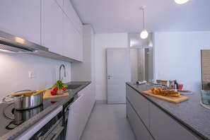 A modern kitchen with a stove, sink, and countertop with food items.