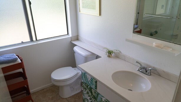 Une salle de bain avec des toilettes, un lavabo et une fenêtre.