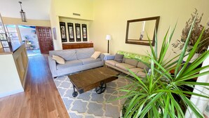 Una sala de estar con un sofá, una mesa de centro y una planta grande.