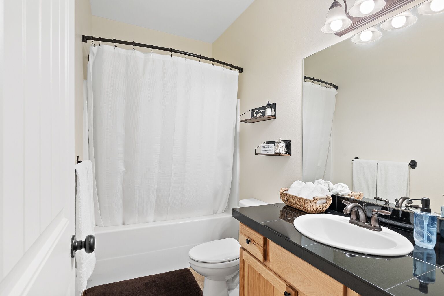 A modern bathroom with a bathtub, toilet, and vanity with a sink and mirror.
