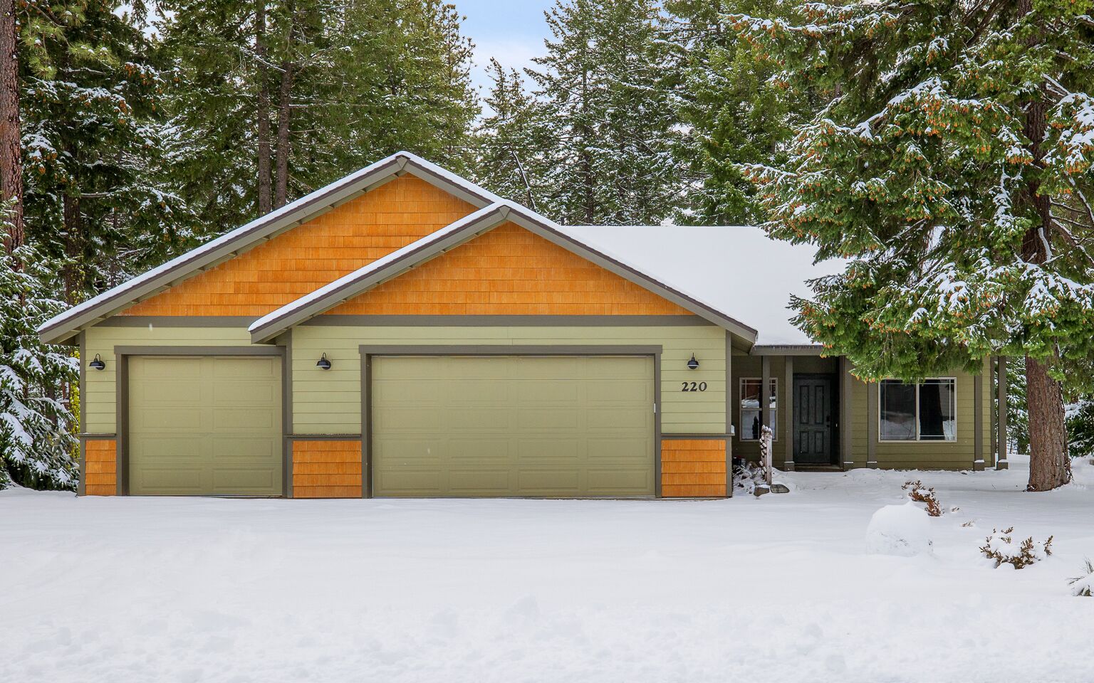 A two-story building with a garage, numbered 220, surrounded by snow-covered trees.