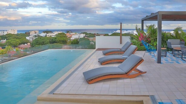 A rooftop pool with lounge chairs and a view of the cityscape. - Nice Studio, Located a few Steps From the 5th av (Playa del Carmen)