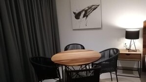 A room with a wooden table and four black chairs, a desk with a lamp, and a painting on the wall. - Nice Studio, Located a few Steps From the 5th av (Playa del Carmen)