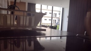 A modern room with a large window, a dining area with a table and chairs, and a view of a building outside. - Nice Studio, Located a few Steps From the 5th av (Playa del Carmen)