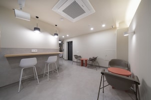 A modern, well-lit room with a bar area, seating, and a door leading to another space.