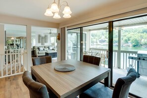 Enjoy meals in this dining area with a table for four, large windows offering views of a body of water and surrounding greenery.