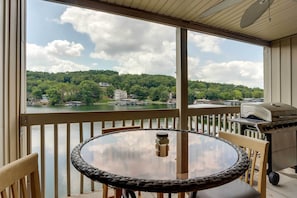 Enjoy a serene lake view from this balcony, featuring a grill and comfortable seating.