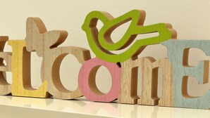 Wooden letters spelling "WELCOME" with a flower decoration on the 'W'.