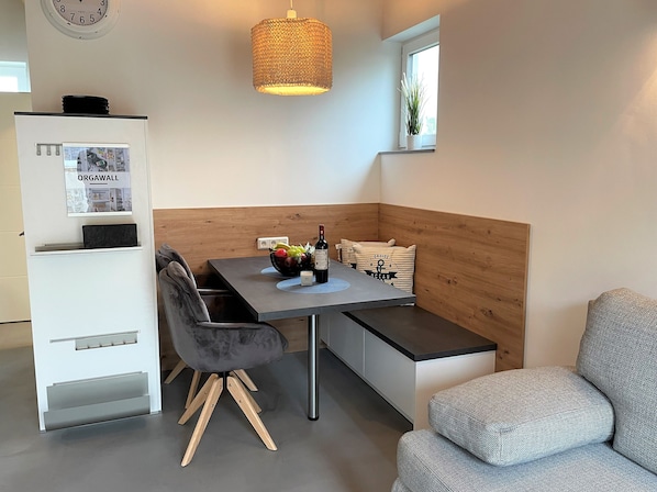 Una cocina moderna con zona de comedor, que presenta una pared de acento de madera, un banco empotrado y una lámpara colgante.