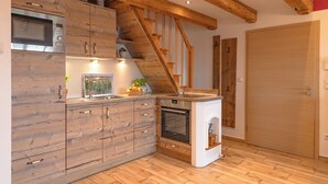 Une cuisine avec des meubles en bois, un four encastré et un escalier en bois.