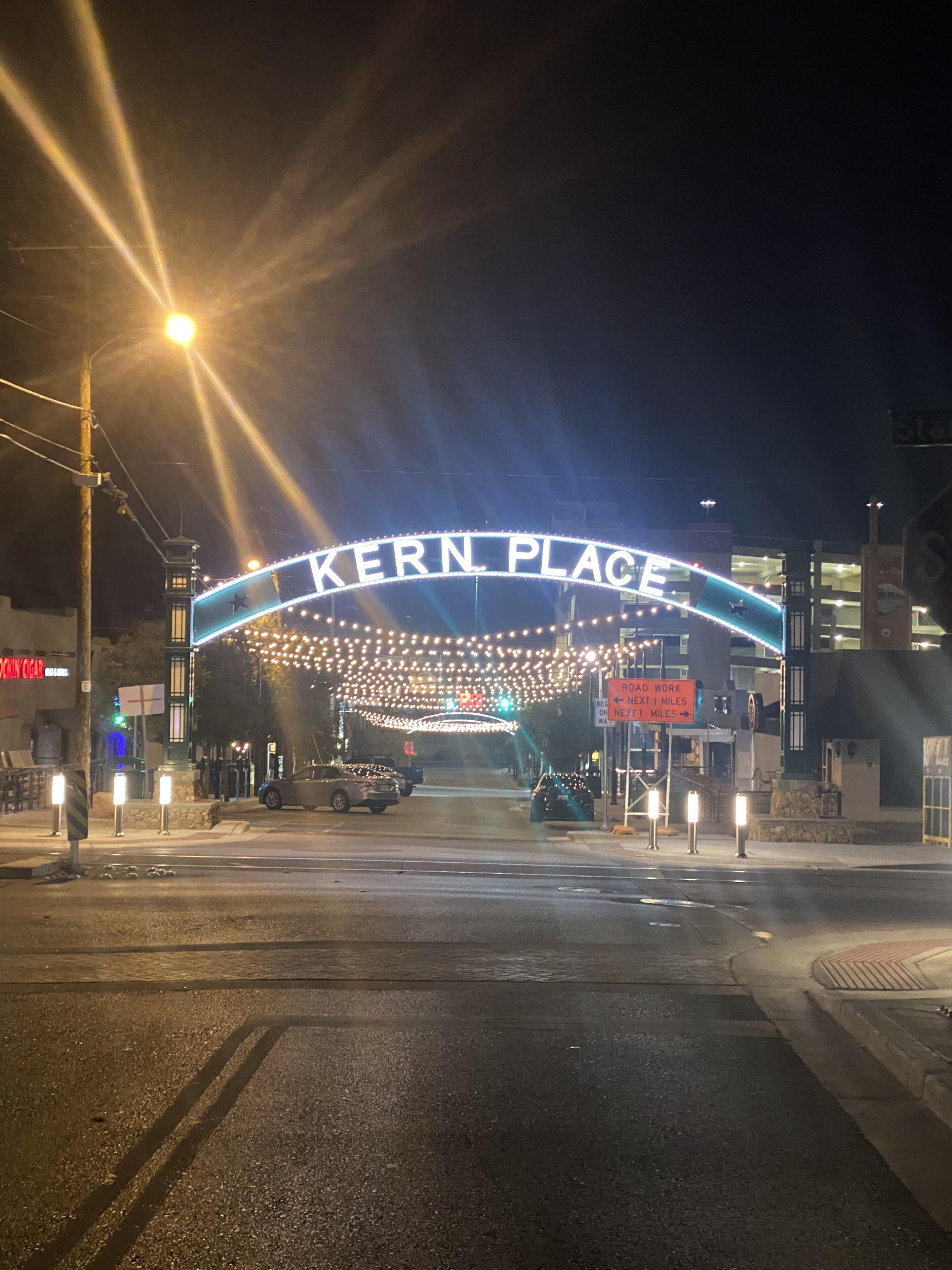 Ein Nachtbild des Eingangs von Kern Place mit beleuchteter Beschilderung und Straßenlaternen.
