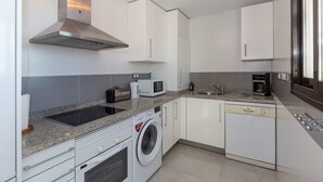 A modern kitchen with white cabinets, a stainless steel range hood, a built-in washing machine, a microwave, and a dishwasher. - Vacation Home Penthouse La Cala De Mijas with Sea View, Pool (La Cala de Mijas)