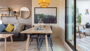 A modern living room with a dining table, chairs, a sofa, a round mirror, a hanging light fixture, and a framed picture on the wall. - Vacation Home Penthouse La Cala De Mijas with Sea View, Pool (La Cala de Mijas)