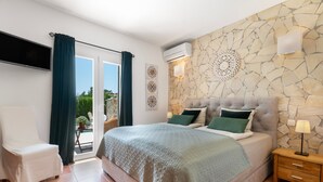 Une chambre à coucher avec un lit, une chaise, une table de chevet, un téléviseur et un mur en pierre.