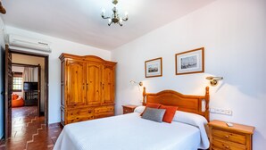 A bedroom with a large bed, wooden wardrobe, bedside tables, and a chandelier. - Holiday Home 'New House In Malaga Nature' with Mountain Views, Wi-Fi and Air Conditioning (Málaga)