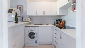 A compact kitchen with a washing machine, a toaster, a sink, and a microwave. - Apartment El Paraiso near Beach with Shared Pool, Balcony, & Wi-Fi (Torrevieja)