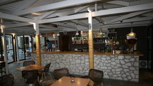 A restaurant with stone walls, wicker furniture, and a bar area with various bottles. - Village Inn Studios & Family Apartments (Zakynthos)
