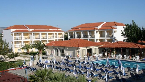 A hotel with multiple balconies, a swimming pool, and sun loungers. - Village Inn Studios & Family Apartments (Zakynthos)