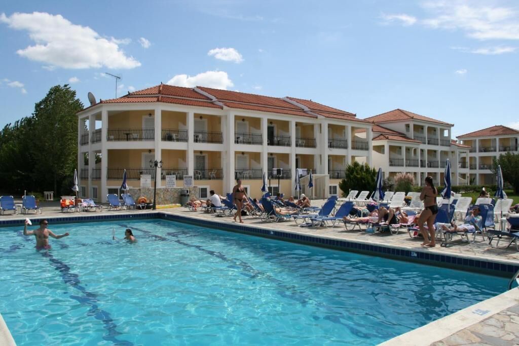 Um hotel com piscina, cercado por espreguiçadeiras e guarda-sóis.