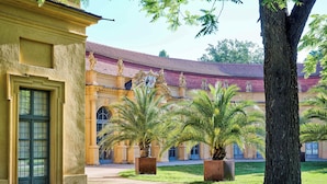 Un patio con palmeras, un edificio de techo rojo y estatuas.