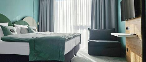 Une chambre d’hôtel moderne équipée d’un lit, d’une chaise, d’un téléviseur et d’une commode en bois.