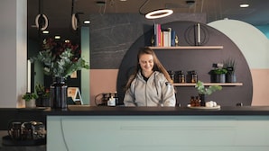 Un mostrador de recepción de diseño moderno, con una pared de mármol, estanterías y plantas decorativas.