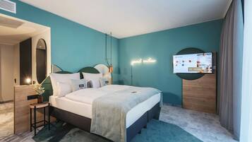 Quarto de hotel moderno com uma cama, televisão na parede, escrivaninha com cadeira e um letreiro de neon.