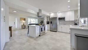 A modern kitchen with white cabinetry, stainless steel appliances, and a herringbone-patterned floor.