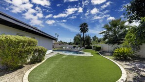 A well-maintained lawn with a swimming pool, surrounded by various plants and trees.