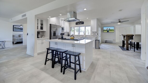 A spacious kitchen with a large island, bar stools, and a dining area with a table and chairs.