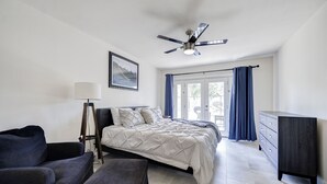 A bedroom with a bed, a desk, a chair, a floor lamp, and a ceiling fan.