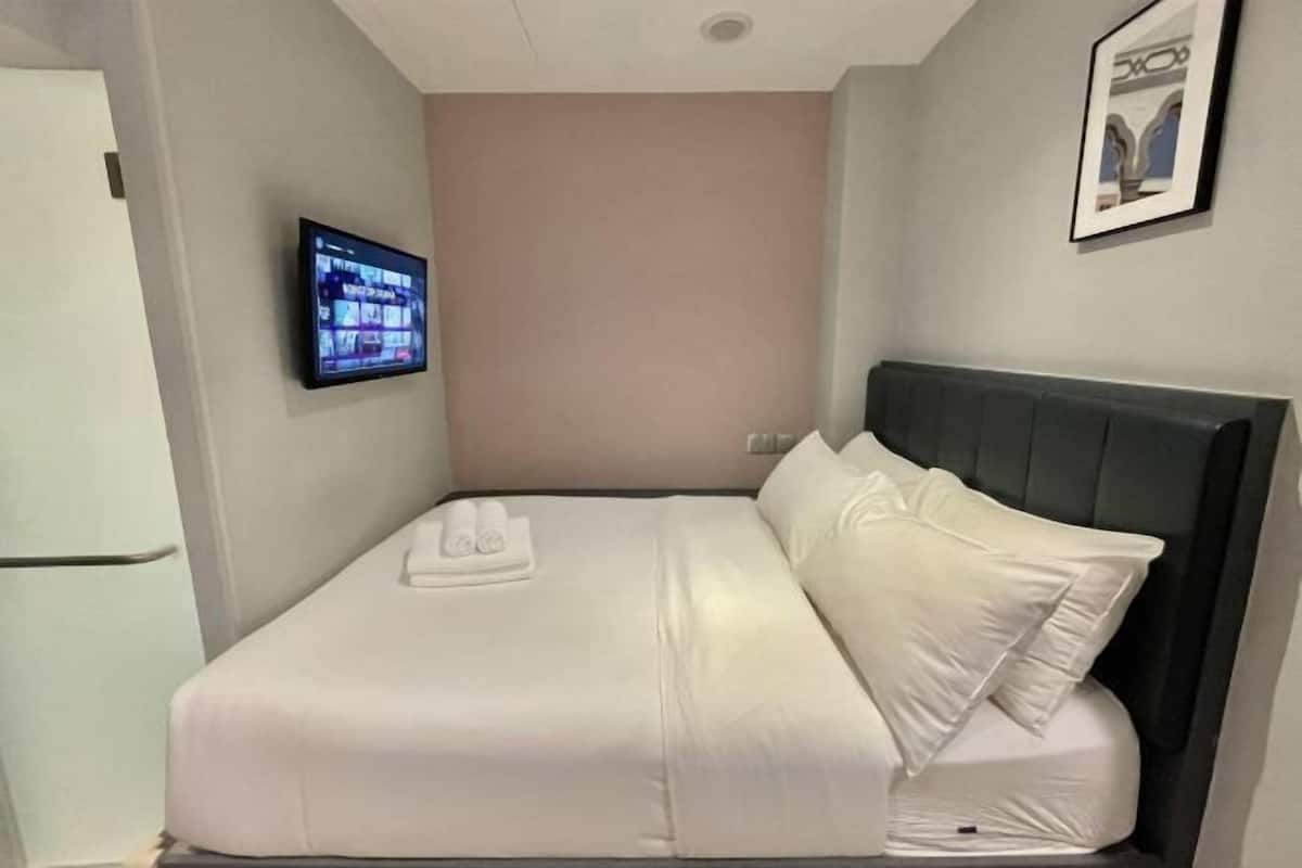 A hotel room with a bed, a flat-screen TV mounted on the wall, and a framed picture on the wall.