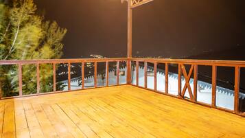 Una terraza de madera con barandilla que da a un paisaje nevado de noche.
